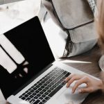 Working Remote - Close-up Photography of Woman Sitting Beside Table While Using Macbook