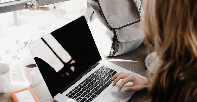 Working Remote - Close-up Photography of Woman Sitting Beside Table While Using Macbook