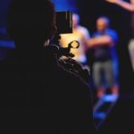 Film Set - Man Standing on Stage Holding Microphone