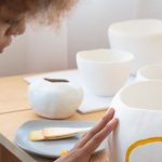 Entrepreneur Skills - From above side view of talented African American female artisan sitting at table in creative workshop and paining picture on handmade ceramic bowl