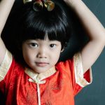 Feng Shui - Calm Asian child holding New Year toy above head and looking at camera
