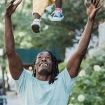 Green Lawn - Cheerful Father Tossing a Baby Girl up in a Residential Area