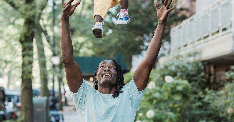 Green Lawn - Cheerful Father Tossing a Baby Girl up in a Residential Area
