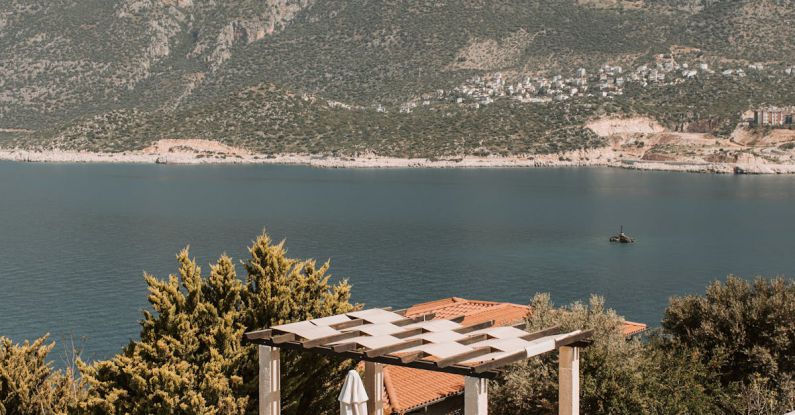 Outdoor Patio - Aerial View Of Pool Lounge And Body Of Water Near Mountain