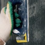 Home Repair Tools - Crop anonymous male worker in gloves holding scraper and aligning walls in flat