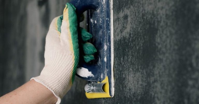 Home Repair Tools - Crop anonymous male worker in gloves holding scraper and aligning walls in flat