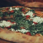 Italian Pizza - A pizza with cheese and tomatoes on top of a wooden board