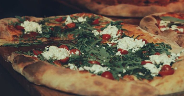 Italian Pizza - A pizza with cheese and tomatoes on top of a wooden board